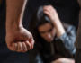 Woman abuse, Young woman scared holding head with hands, male clenched fist close up. Domestic violence, husband against wife. Dark room background